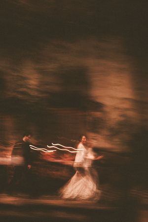 Blurred motion capture of dancers in formal attire creating ethereal light trails against a dark background.