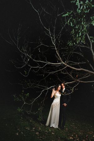 A series of nighttime photos showing figures in white dresses illuminated against dark trees and foliage.
