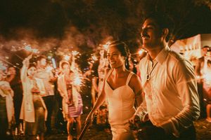 A crowd of people dancing and celebrating at a lively nighttime event with warm orange lighting.