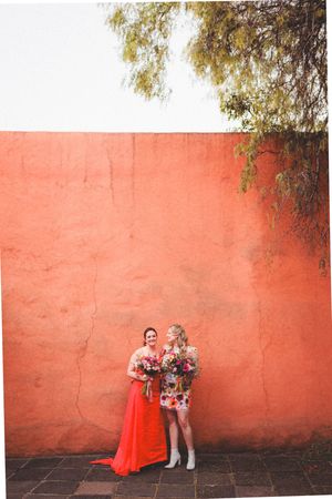 Three artistic photos against a coral-colored wall show figures in red outfits with flowers creating a minimalist composition.