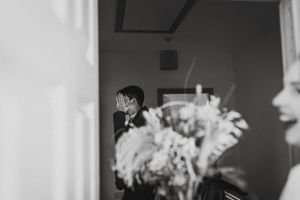 Black and white photo showing a blurred floral arrangement in the foreground with a silhouetted figure in the background.