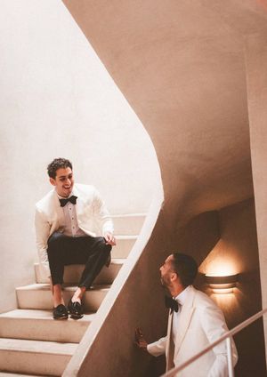 Two people having a conversation in a minimalist white interior space with angular architectural details and warm lighting.