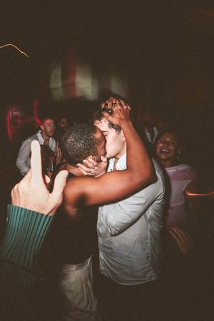 Two people dancing and laughing together in a dimly lit room with joyful expressions.