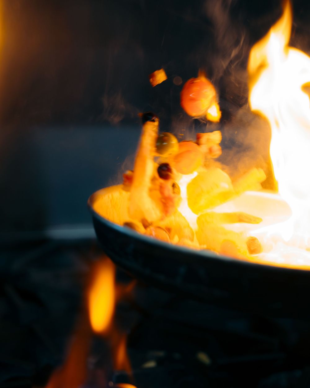 Dramatic flambé cooking with flames engulfing pasta in a pan over open fire.

Vancouver Canada Scene