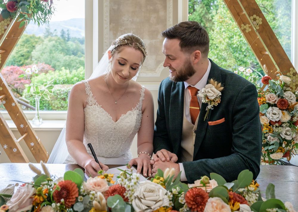 Bride signing wedding schedule while groom looks on at Merewood Country House Hotel