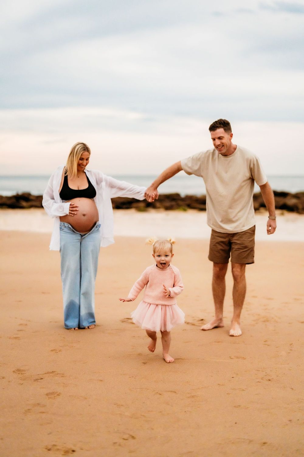 Family enjoys playful moments together on a sandy beach at sunset, creating cherished memories for their photoshoot