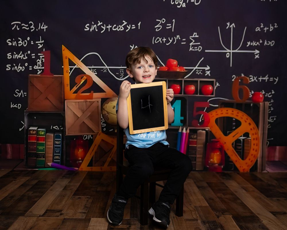 A child plays in front of a large chalkboard wall covered in mathematical equation for 4 year old birthday photoshoot