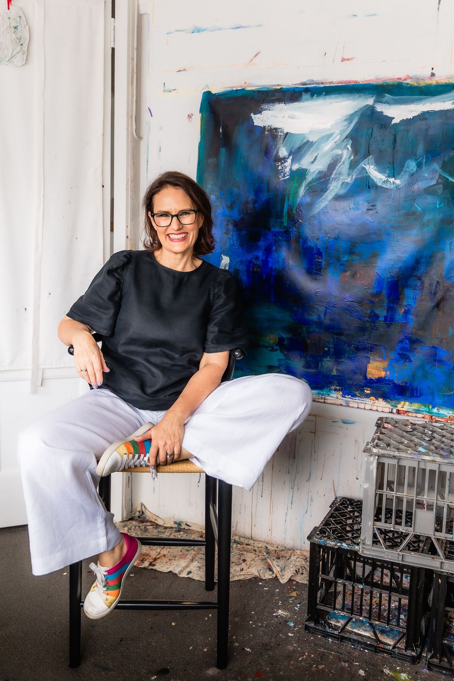 Nicole Fearfield, Abstract Artist, poses for a portrait against one of her paintings in the studio.
