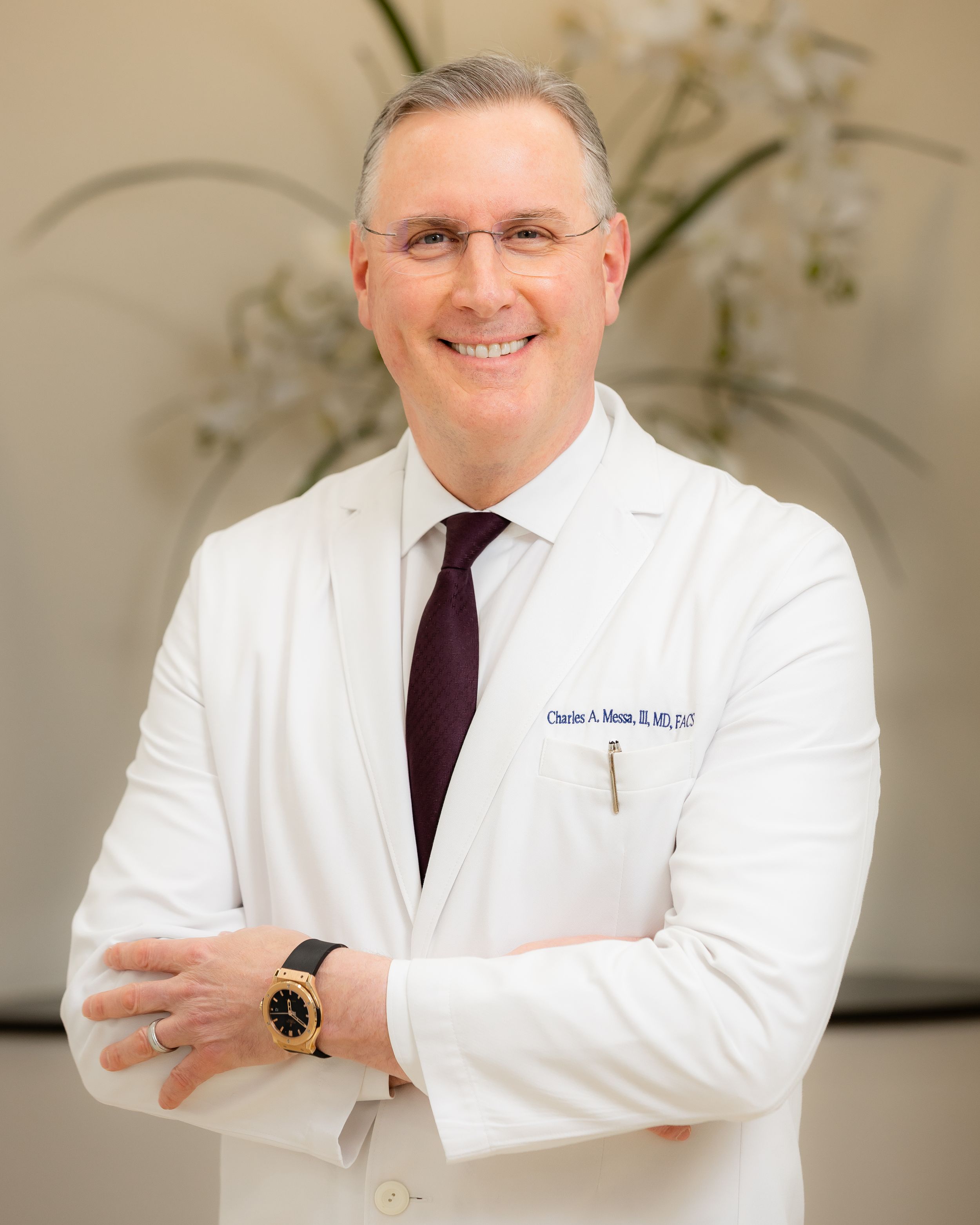 Medical professional wearing white lab coat and burgundy tie poses against light backdrop in professional portrait series.