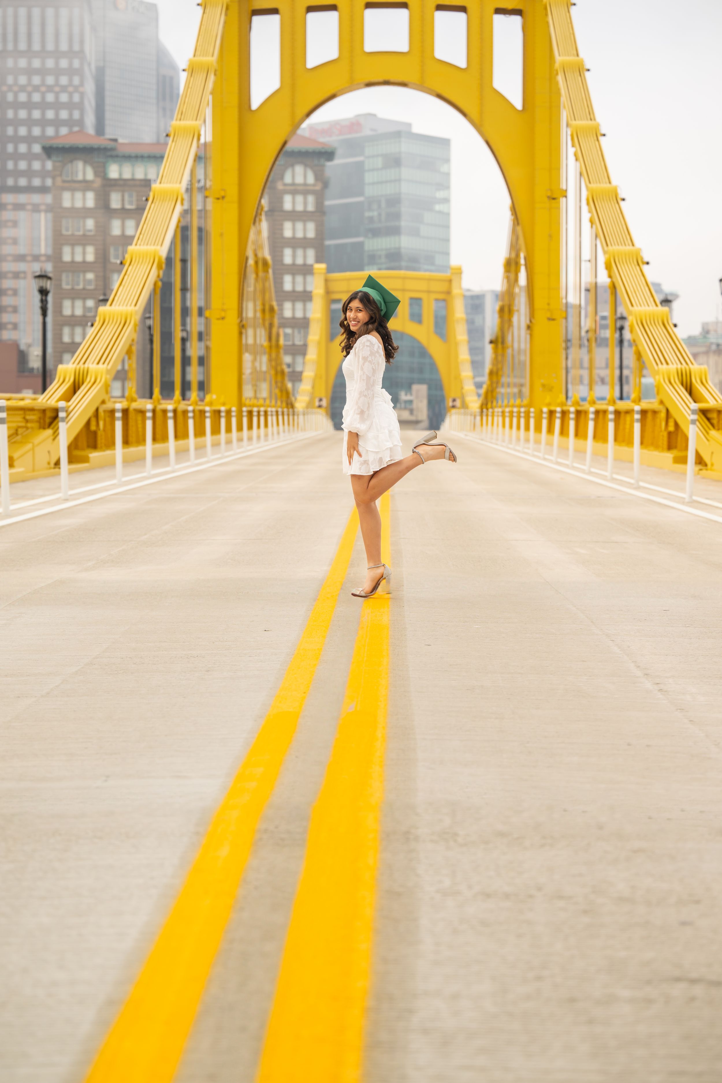 A person walks along a bright yellow bridge with geometric arches against an urban cityscape backdrop.
