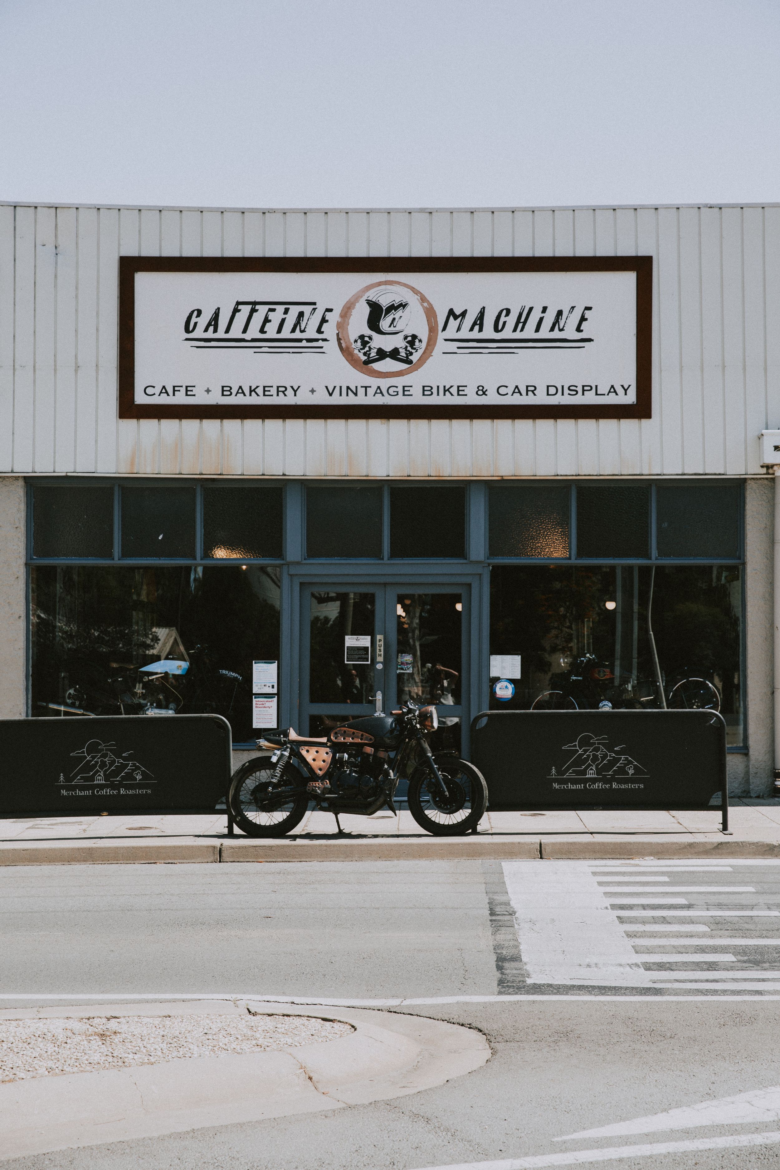 Modern cafe and motorcycle display storefront with minimalist black and white signage and clean exterior design.