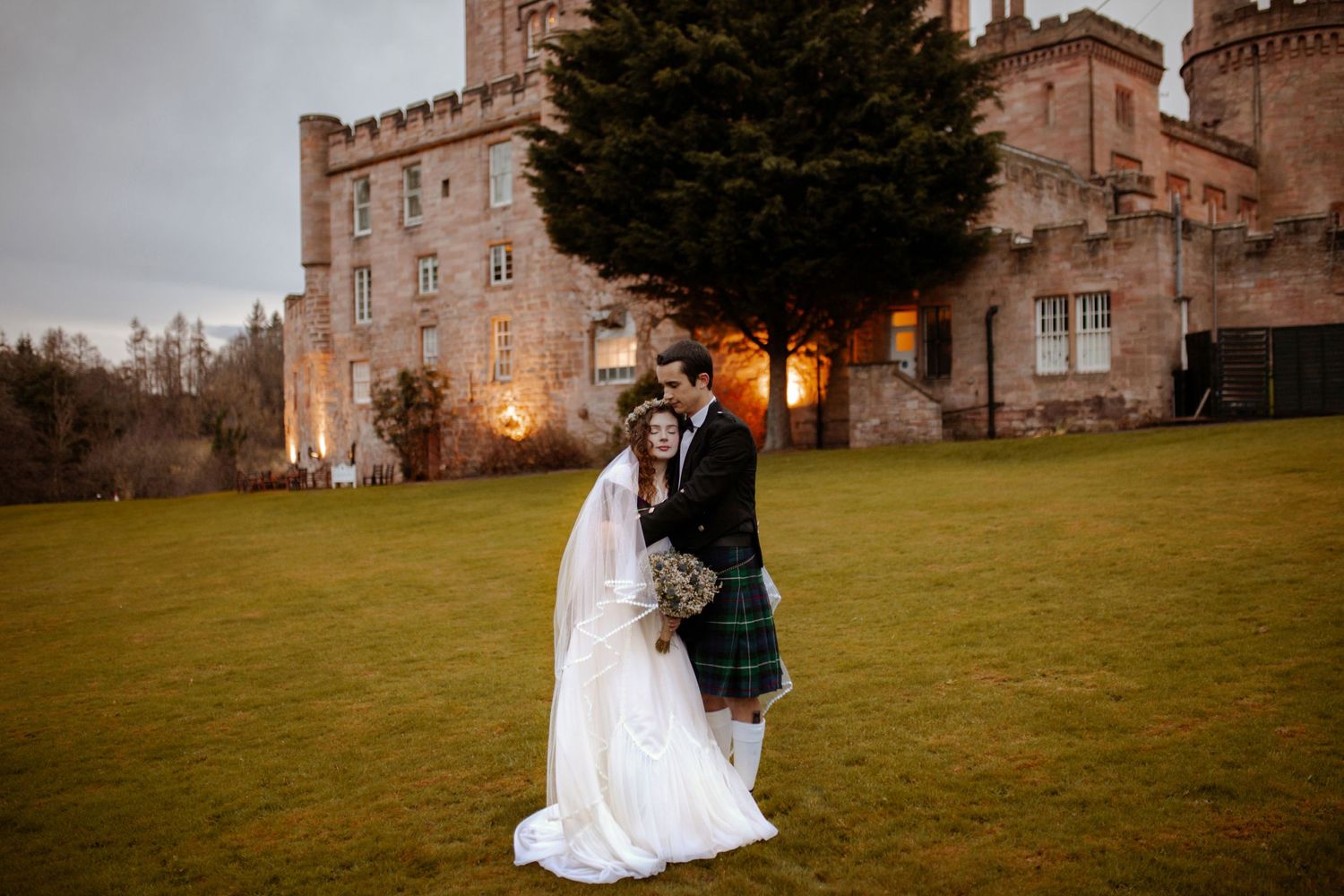 Evening wedding photos at a majestic castle with warm glowing lights.