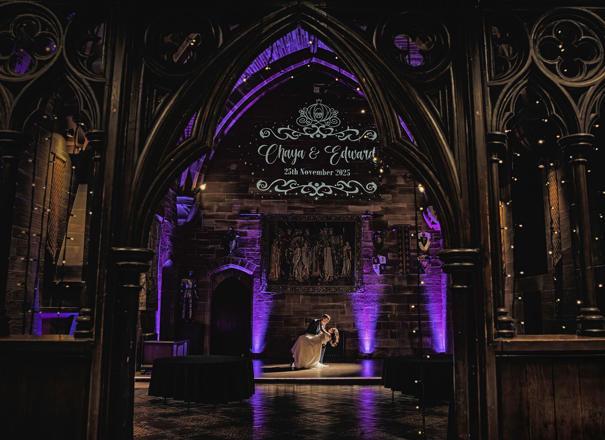 Couple sharing a romantic moment in a gothic cathedral with purple uplighting and personalized wedding name projection.