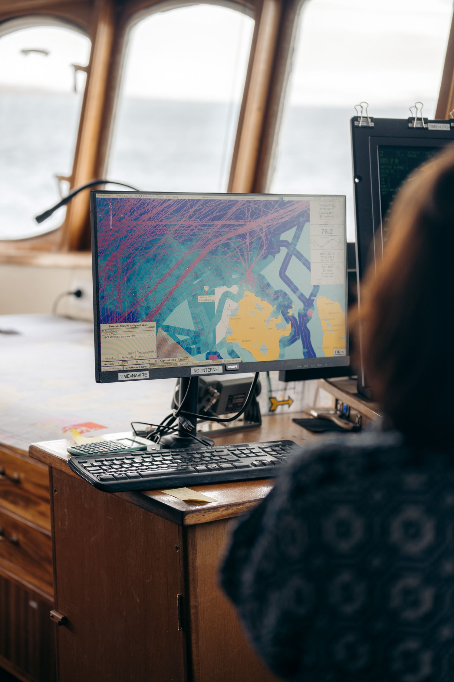Écran de navigation affichant la carte marine, passagère de dos au premier plan