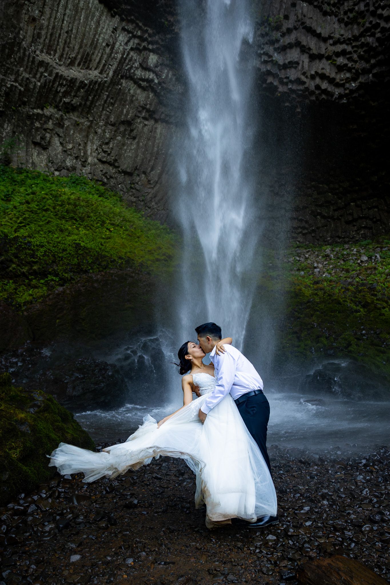 Couple sharing a kiss in front of an Oregon waterfall during their Pacific Northwest Elopement.