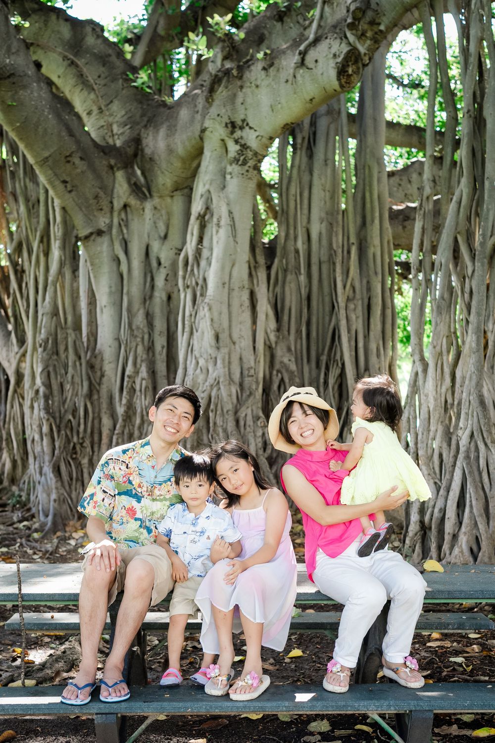Family of five sitting together under a banyan tree at Kapiolani Park during an Oahu family photography session