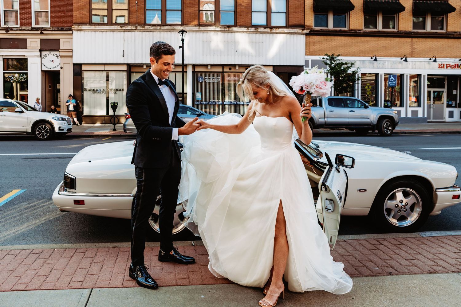 Groom helps his bride exit their vintage Jaguar for an elopement at the Monongalia county courthouse for an elopement in Morgantown, WV