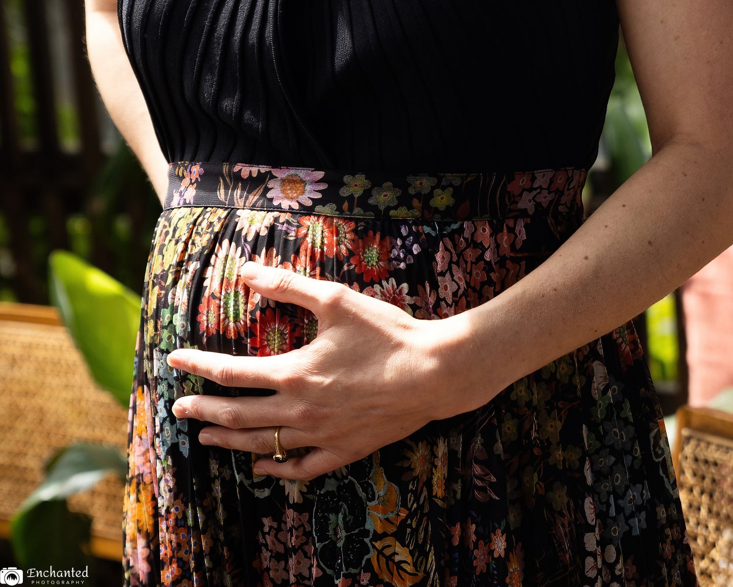 Close-up outdoor maternity portrait of hands resting lovingly on a pregnant belly