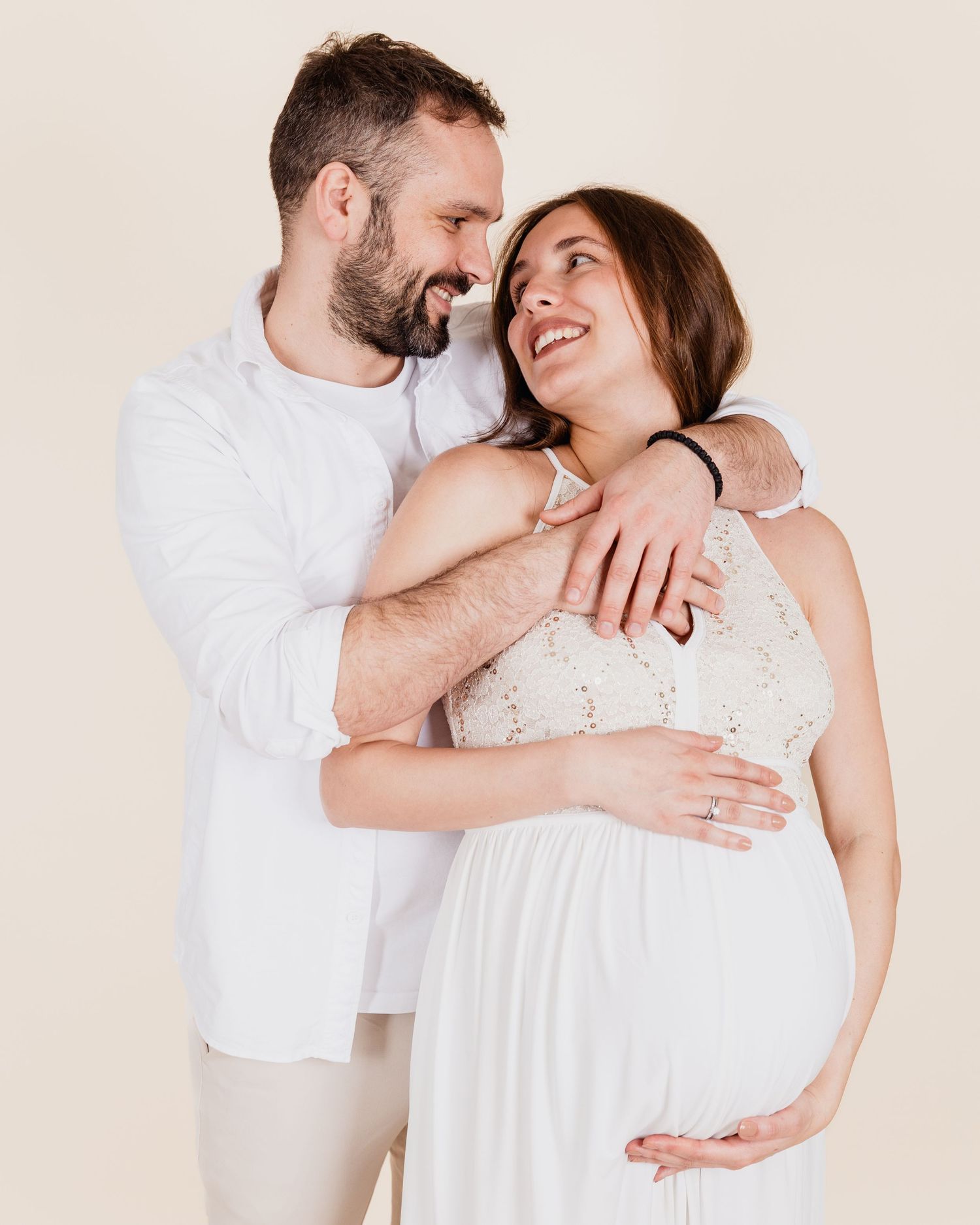 Expectant parents smiling at each other during a relaxed studio maternity portrait