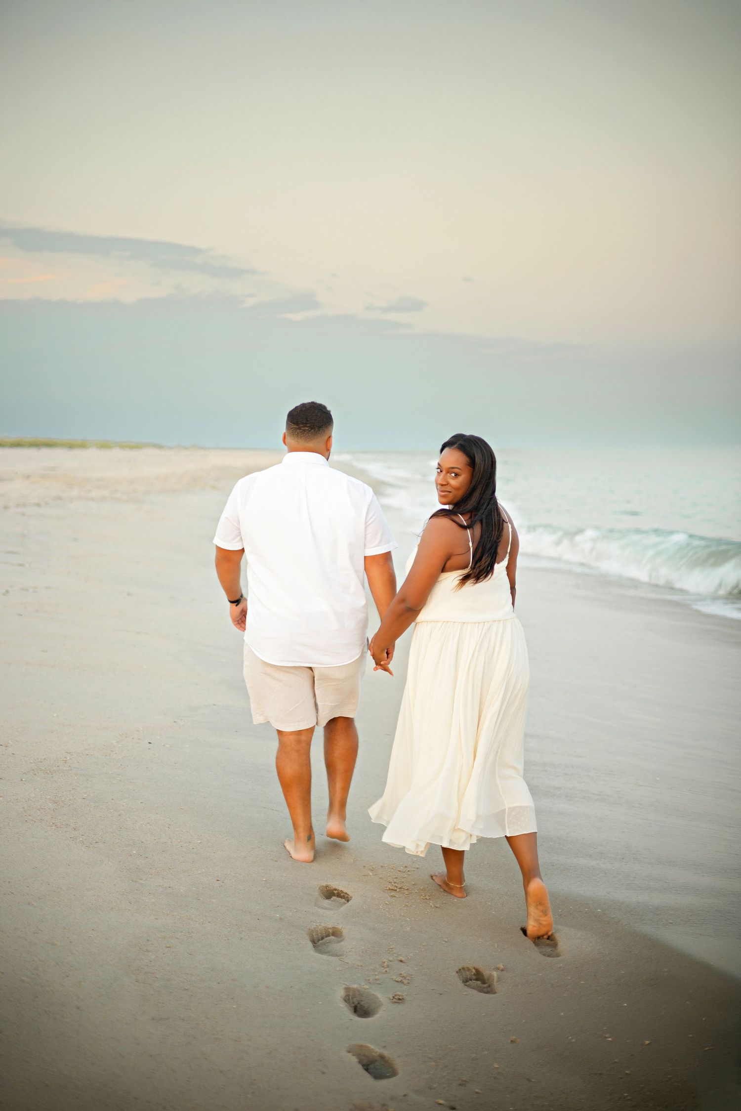 A romantic proposal scene set between rows of grapevines in a scenic vineyard with white flowers and a blanket.