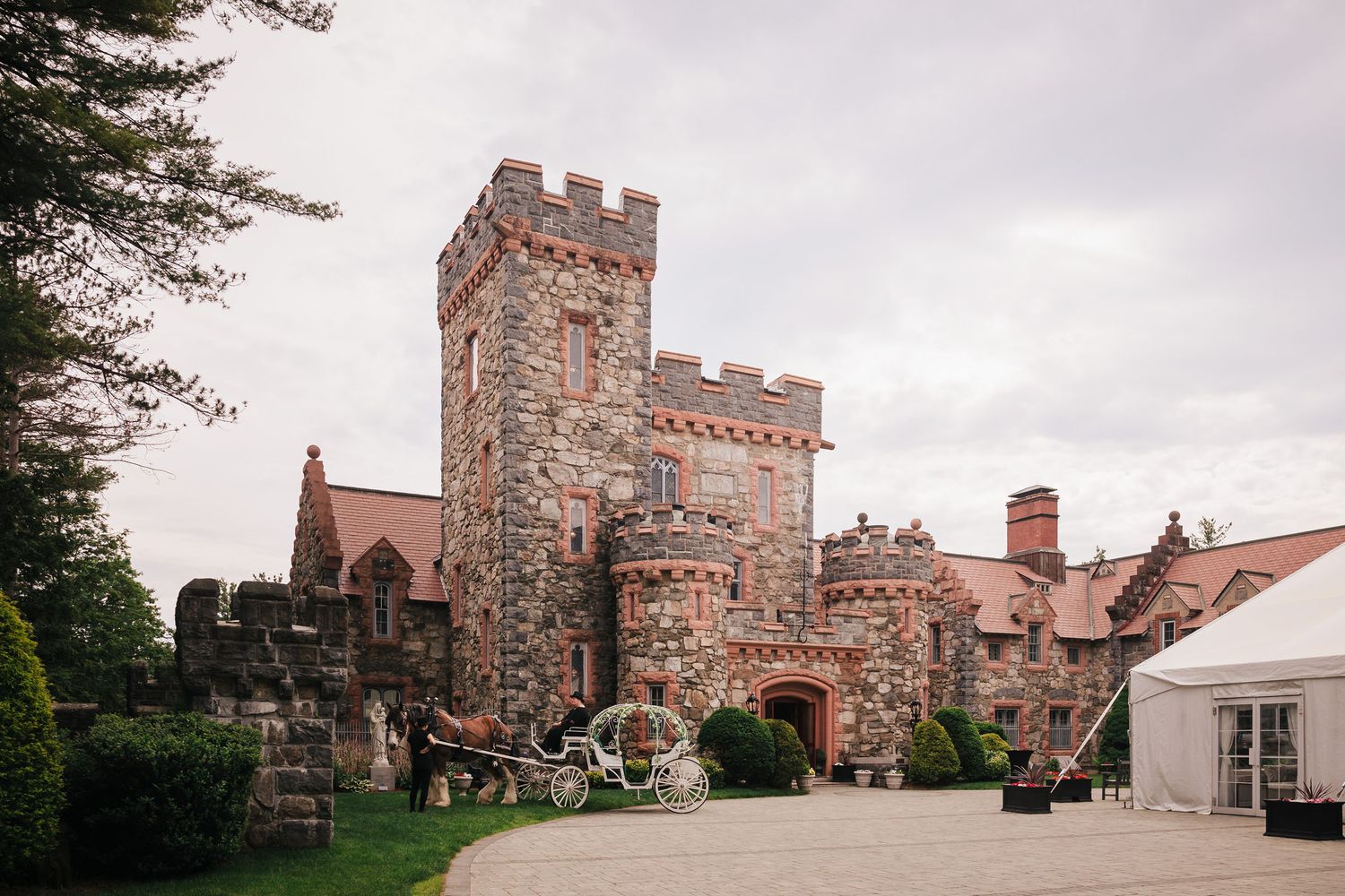 Searles Castle exterior in Windham, New Hampshire, with a white horse-drawn carriage waiting in the driveway before the wedding.