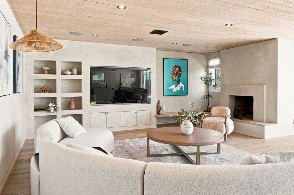 Modern living room with sectional sofa, built-in shelving, wall-mounted TV, fireplace, and wood ceiling accents.