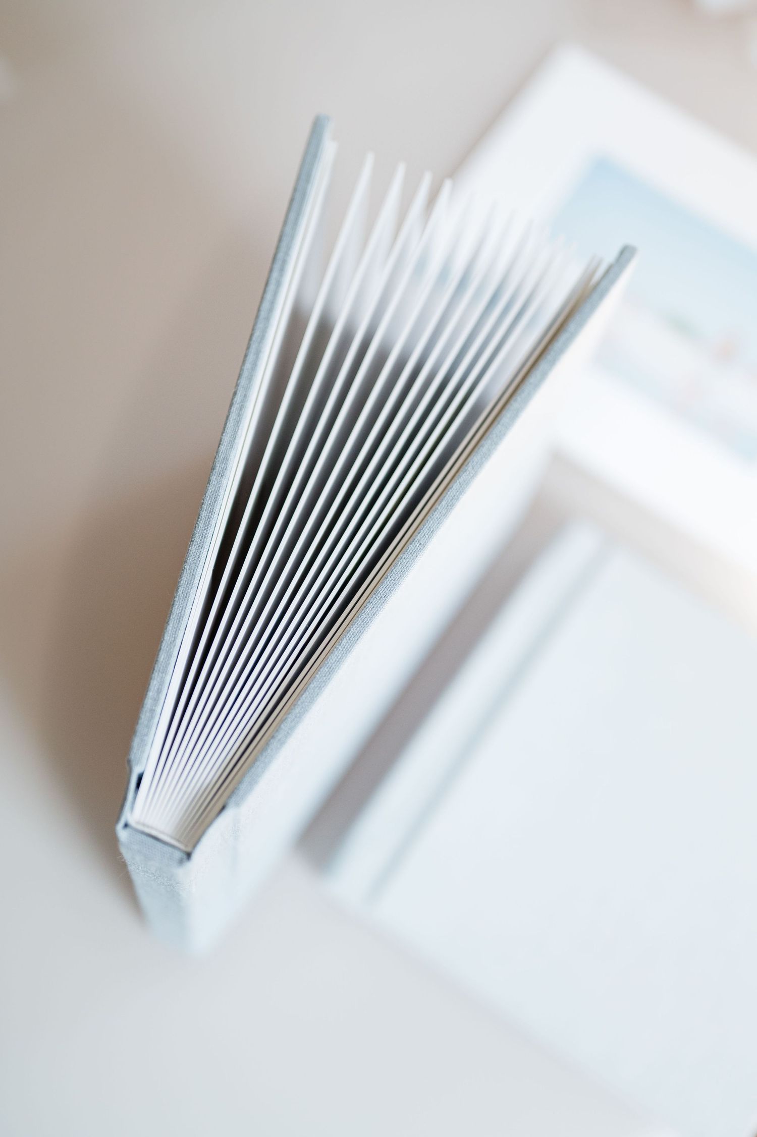 A hardcover book standing upright with fanned pages viewed from the spine on a white surface.