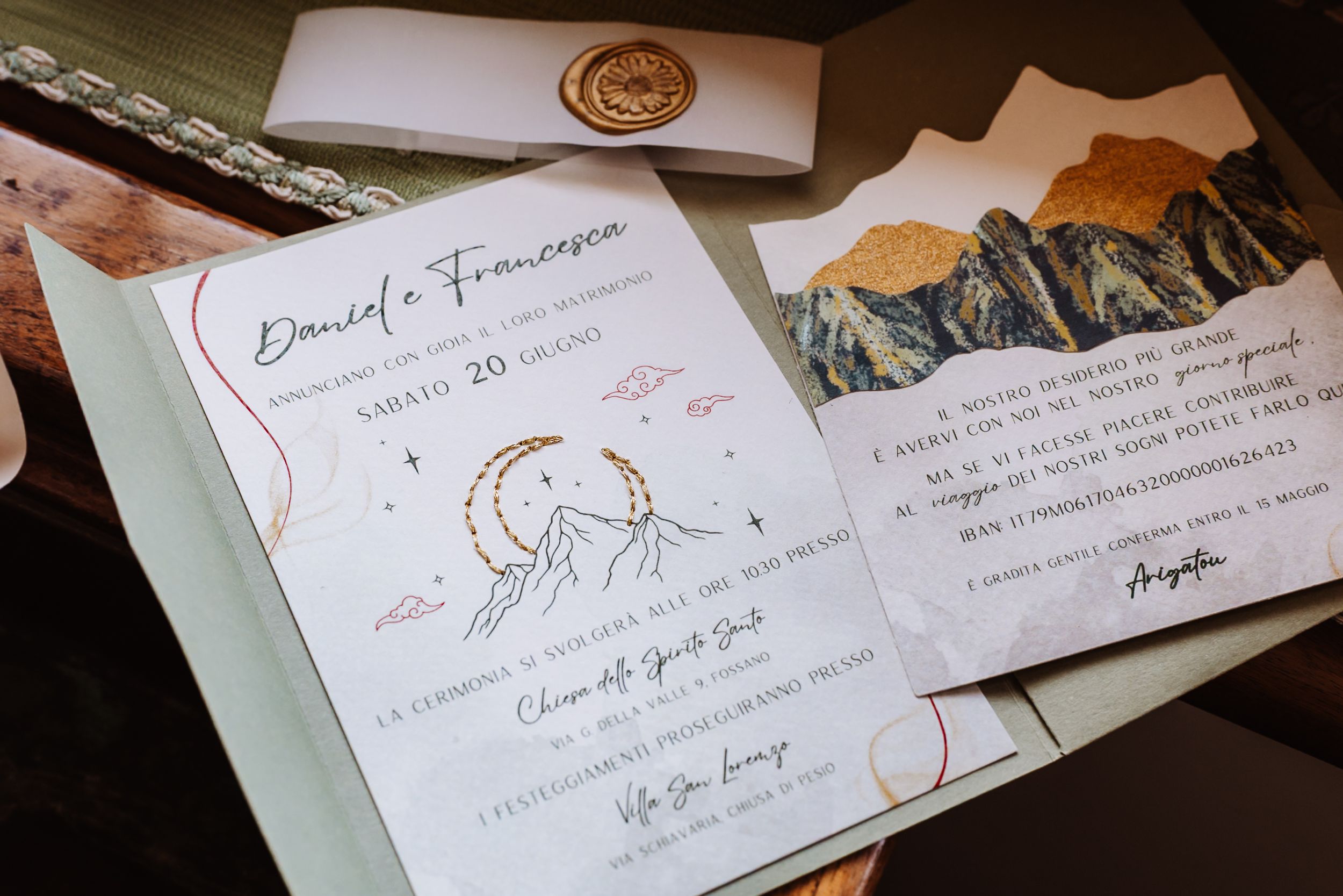 Elegant Italian wedding invitation suite with mountain watercolor design, wax seal, and handwritten calligraphy on wooden surface.