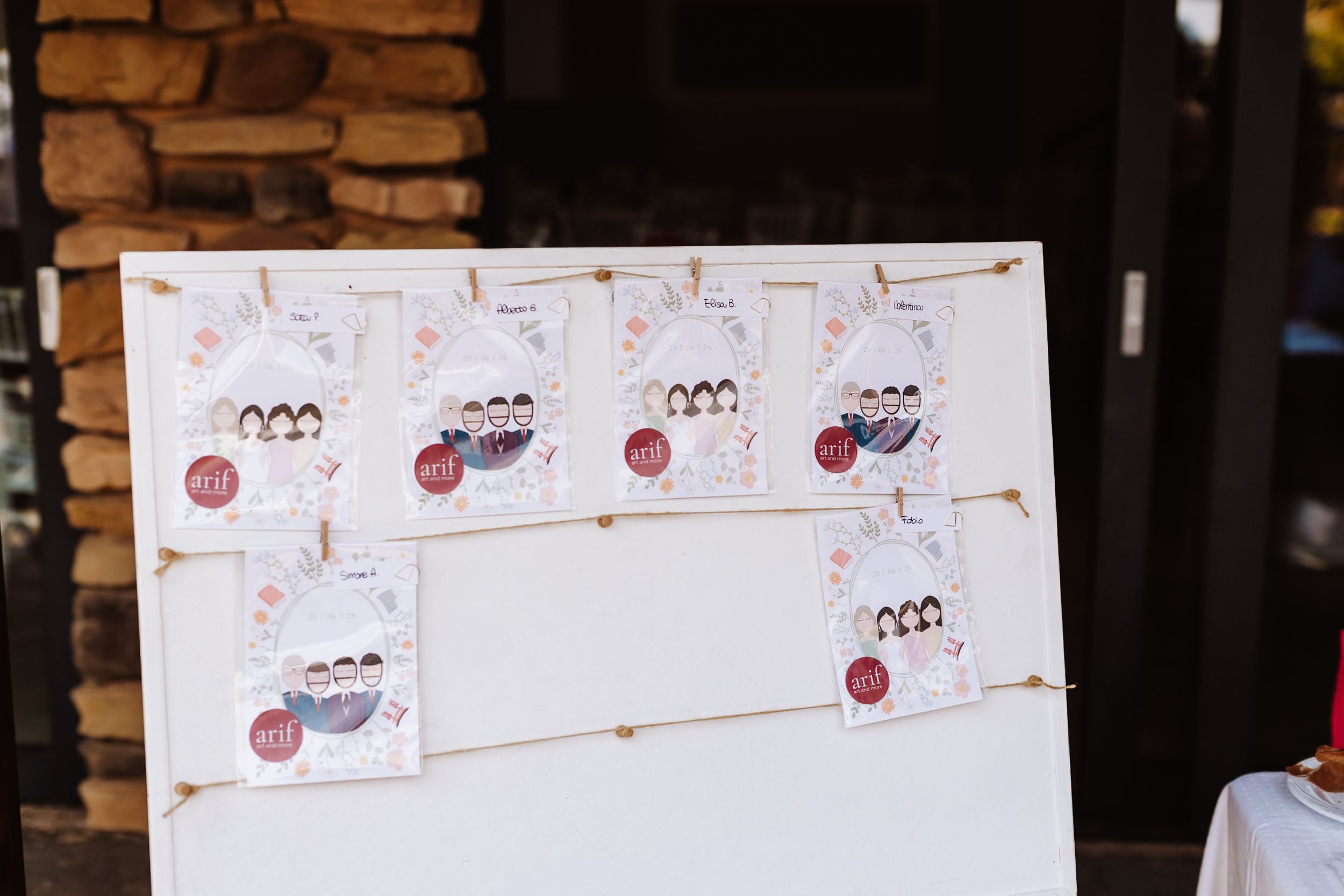 Wedding seating chart display board with illustrated cartoon cards hung on twine.