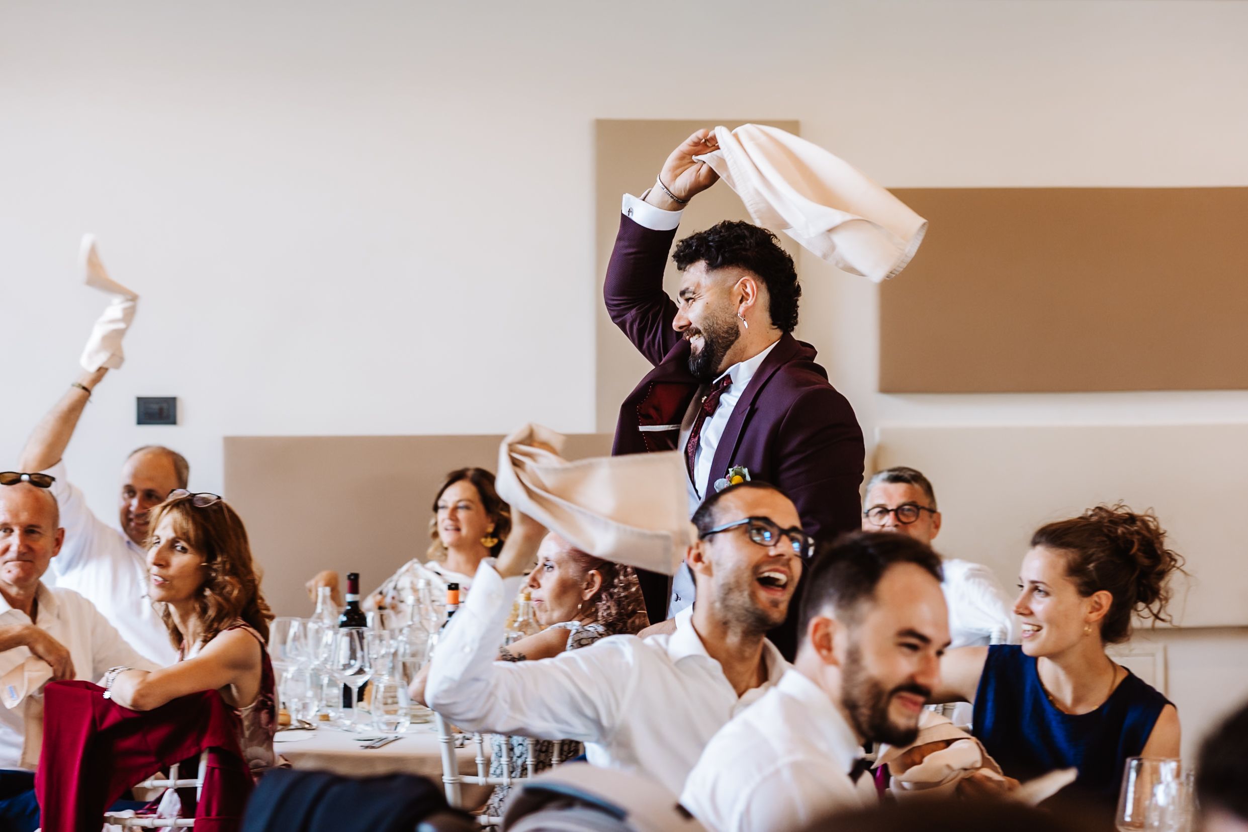 Joyful wedding guests waving white napkins in celebration at a festive reception dinner party.