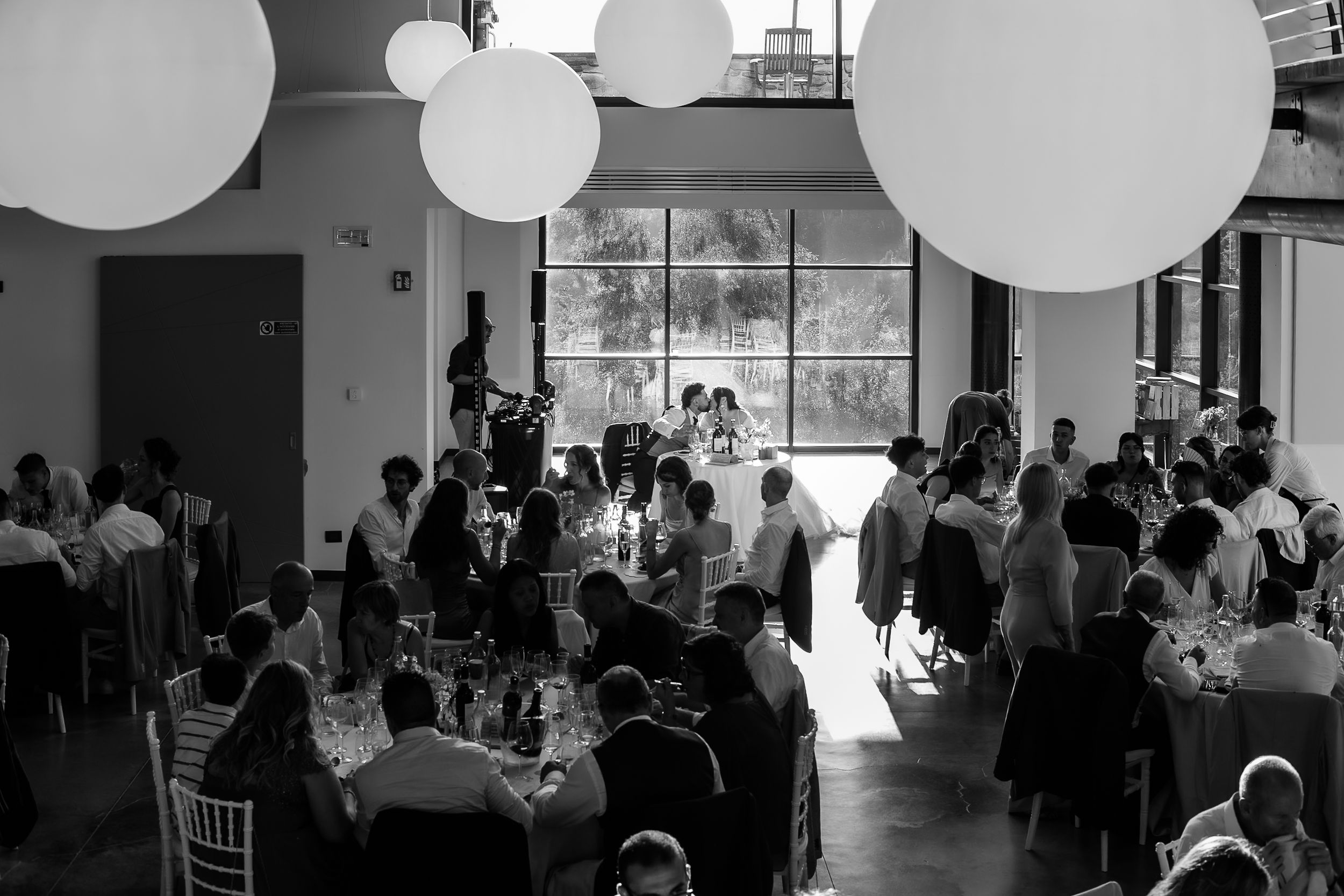 Black and white wedding reception in elegant venue with round balloon lights and guests seated at decorated tables.
