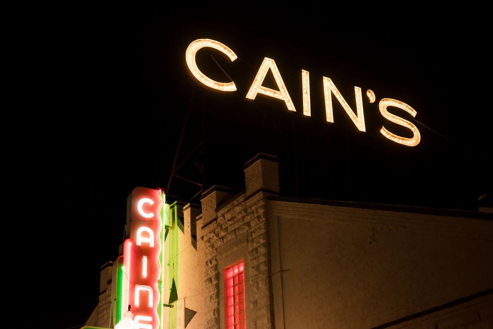 Vintage illuminated Cain's Ballroom sign in Tulsa, OK glowing against dark night sky.