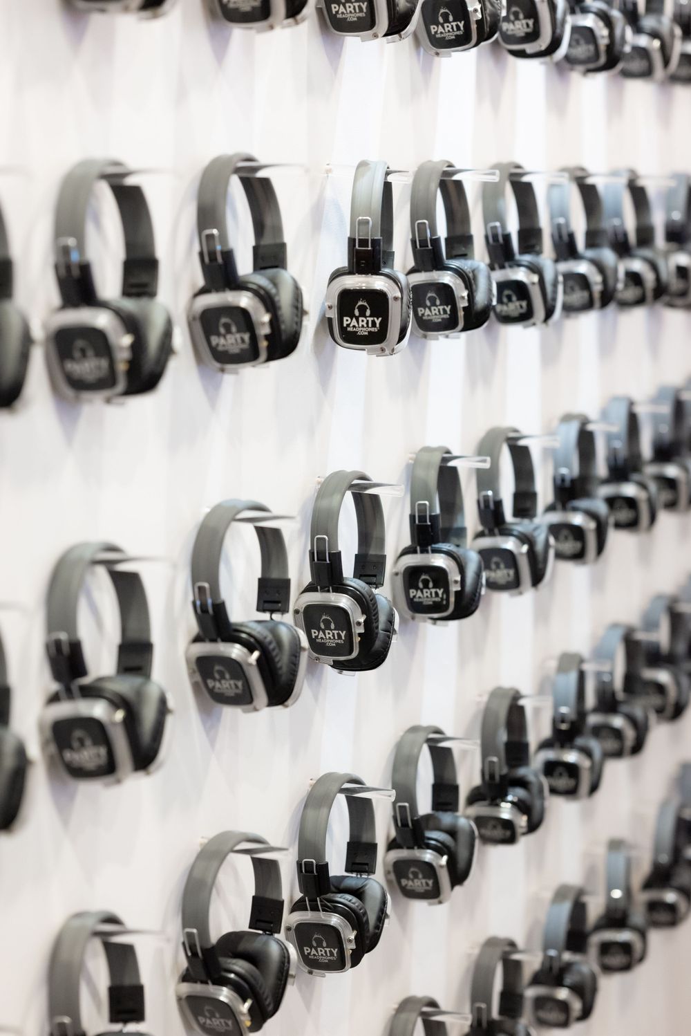 Rows of black headphones mounted on a white wall in a symmetrical display pattern.