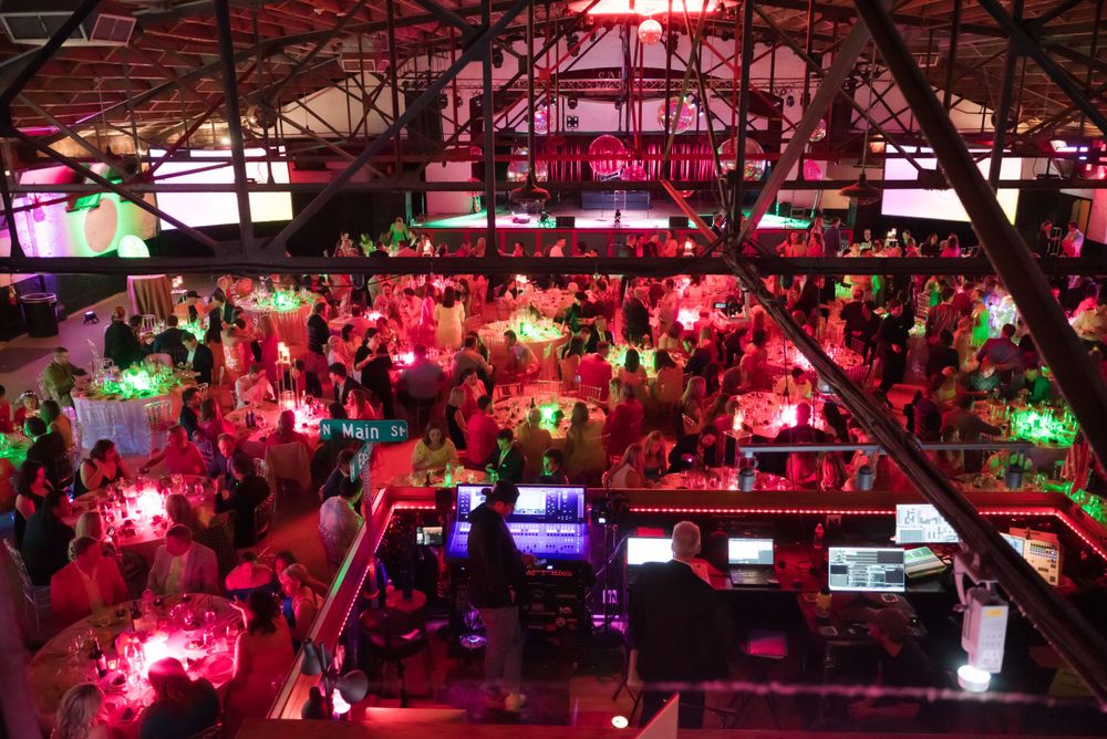 Colorful nightclub interior with vibrant red and green lighting illuminating a crowded dance floor.