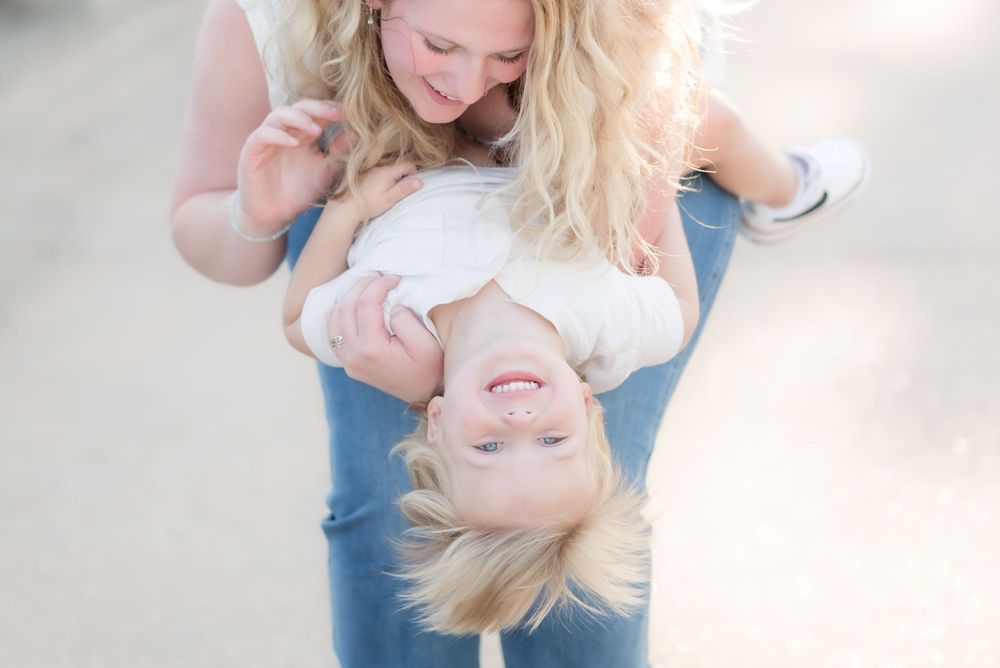 Playful upside down moment captured in casual denim against a soft blurred background.