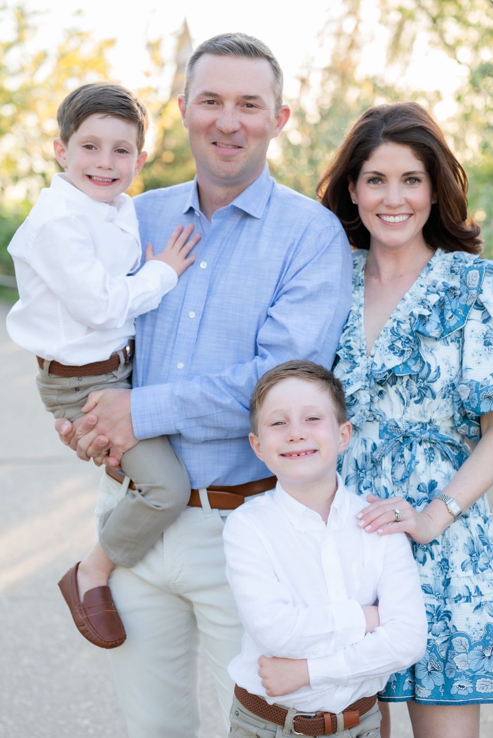 Outdoor family portrait featuring coordinated outfits in blue and white tones.