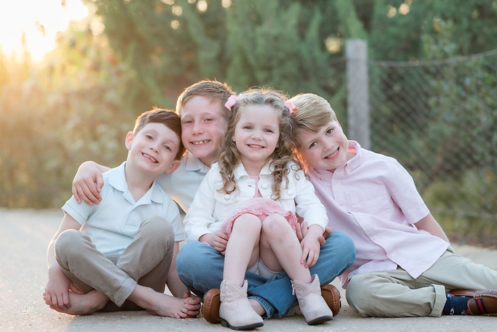 Siblings sitting together on a path during golden hour outdoor photo session.