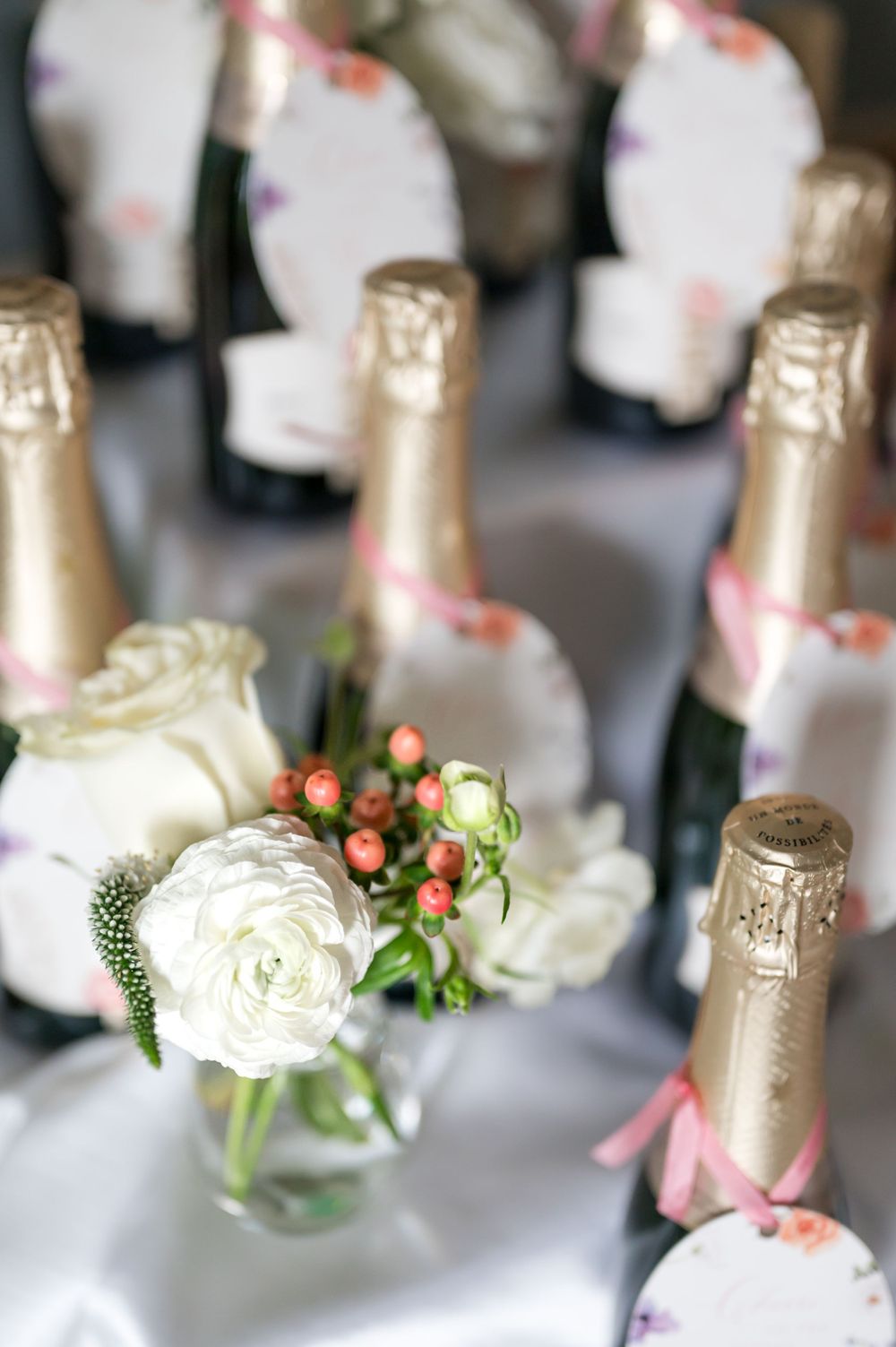 Champagne bottles decorated with pink ribbons and white roses for wedding celebration.