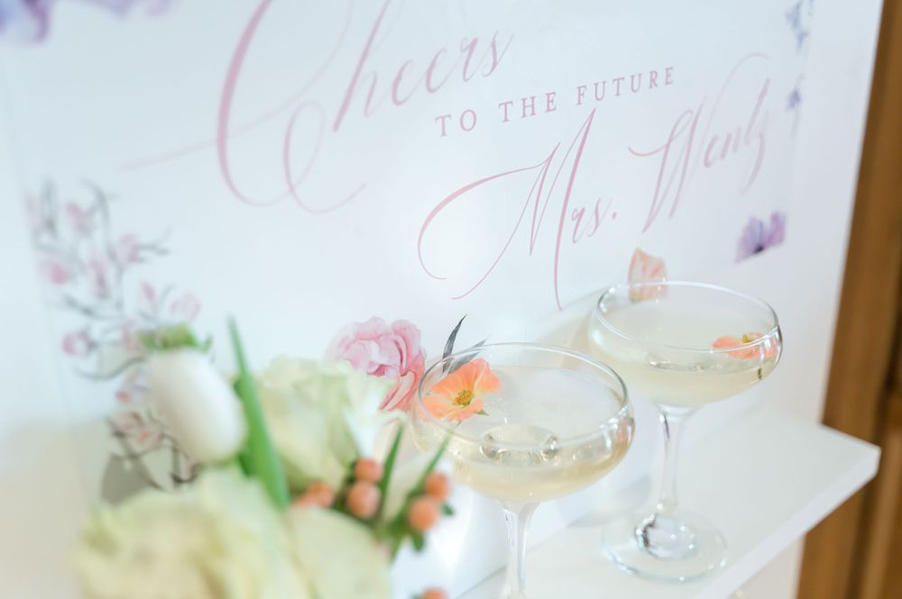 Elegant cocktail display with floral signage and champagne glasses.