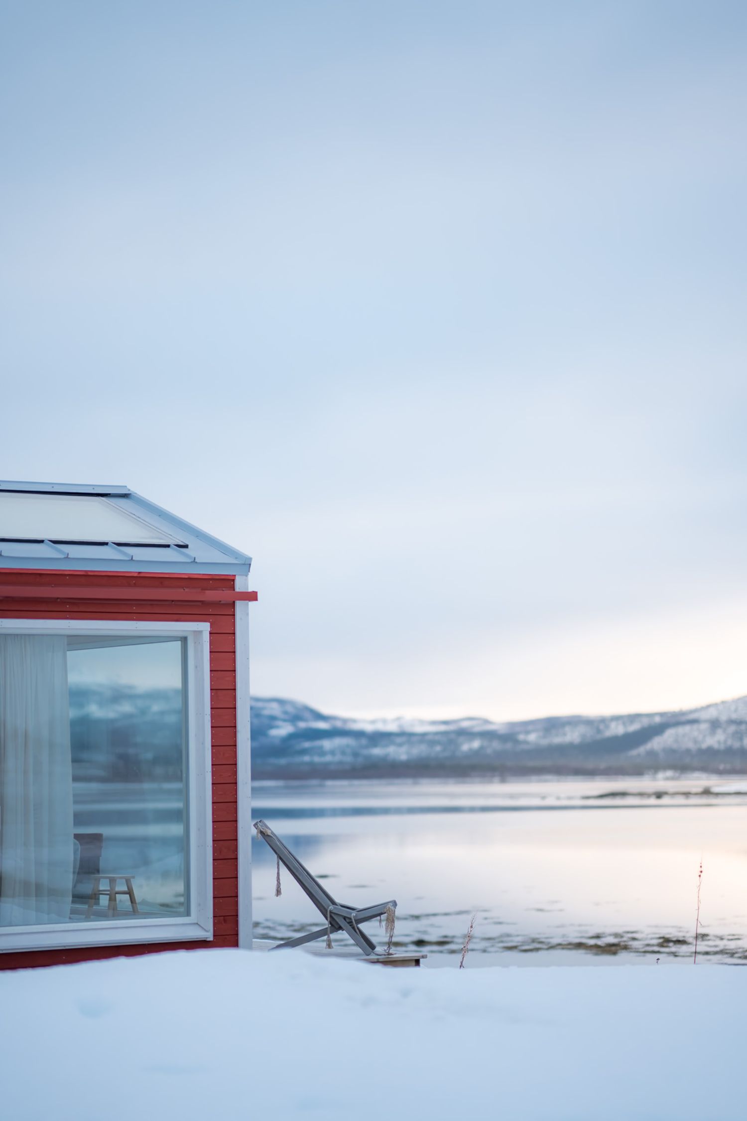 hotel en baie vitrée face au fjord avec un transat sur la terrasse enneigée