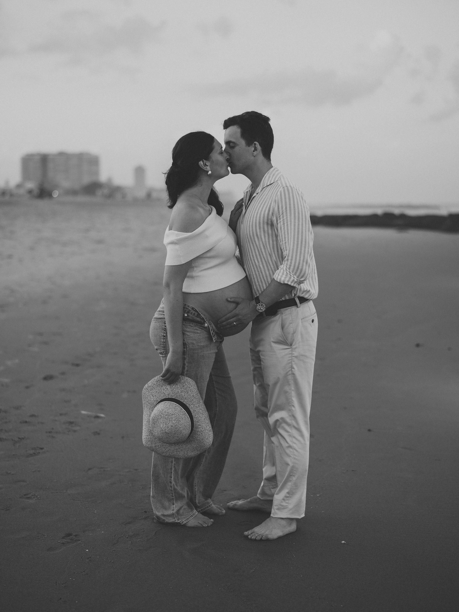 Black and white grainy film image of couple kissing on the shoreline in nj.