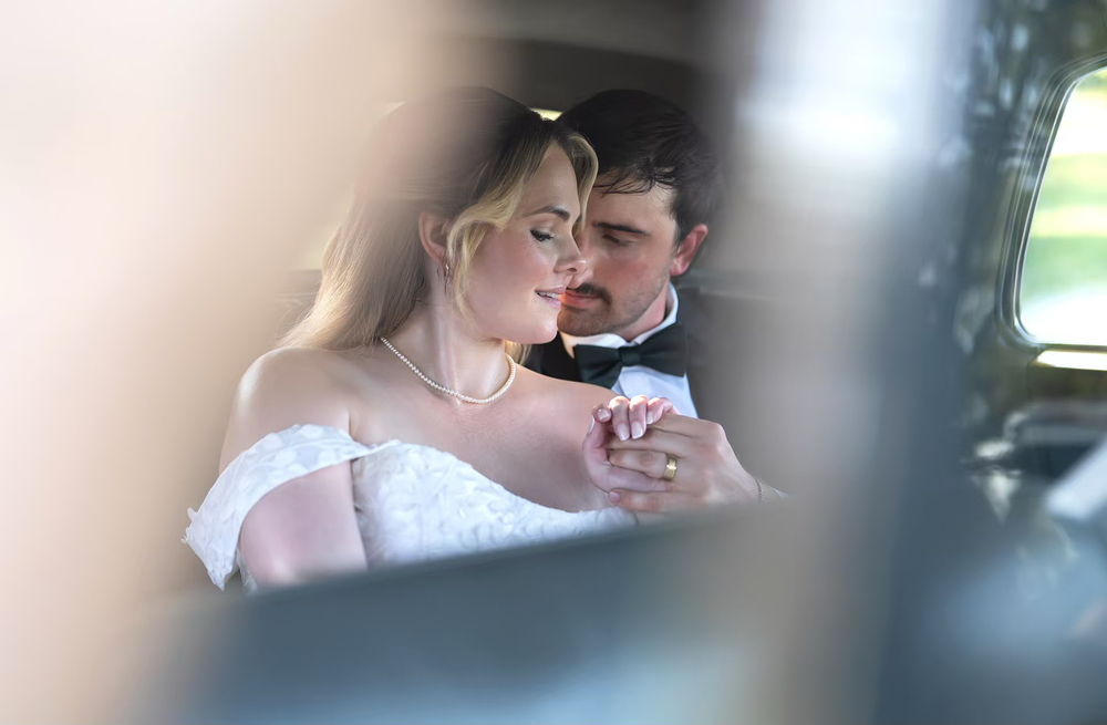 Bride and groom share a romantic moment in a luxury car on their wedding day.