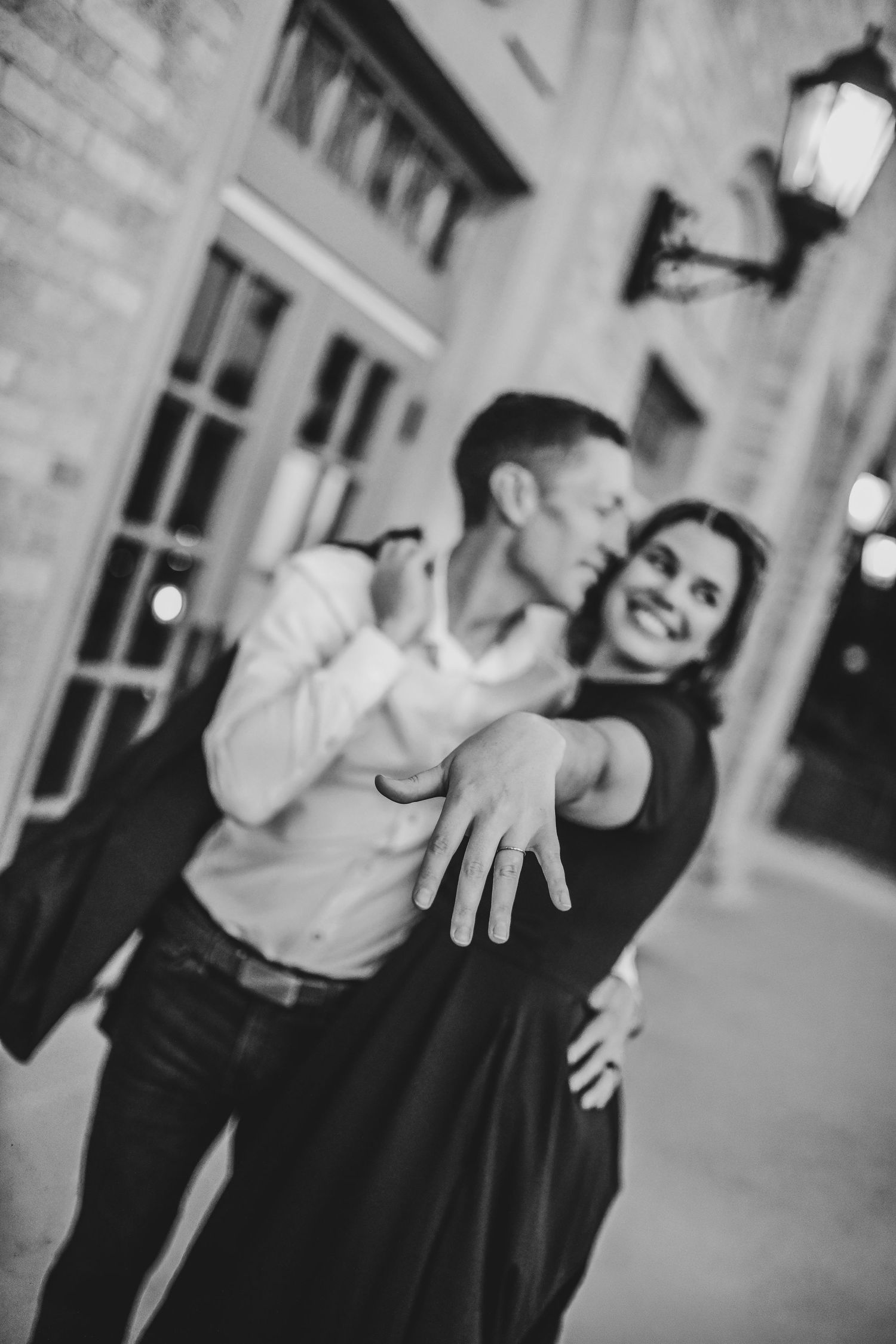 a newly engaged couple show off the engagement ring during their engagement photos on Denton Square