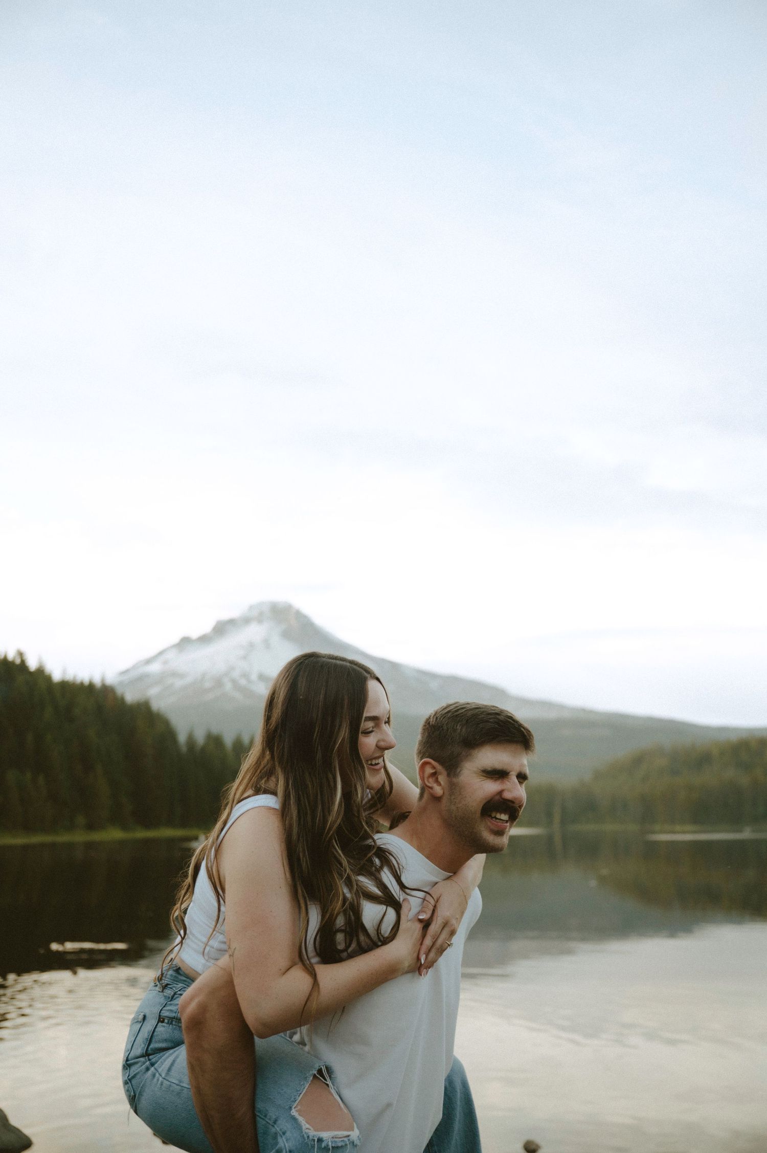 A group of people wearing formal black attire stand together on a sandy beach during overcast weather.
