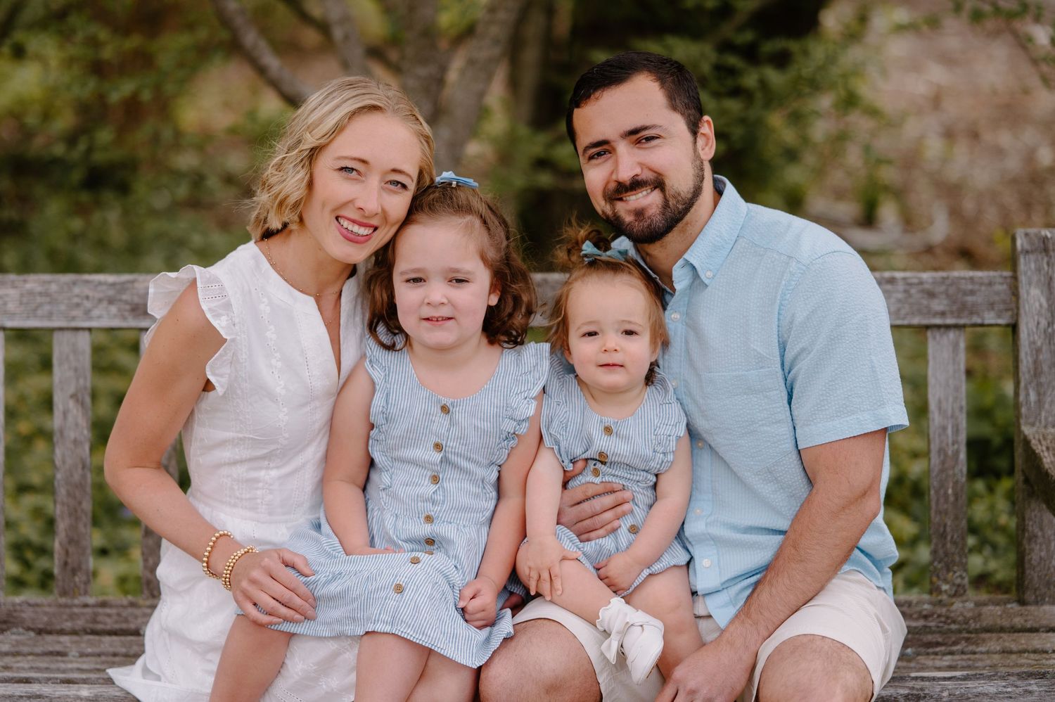Happy family of four smiling on a wooden bench in Ault Park Cincinnati OH by K Herman Photography