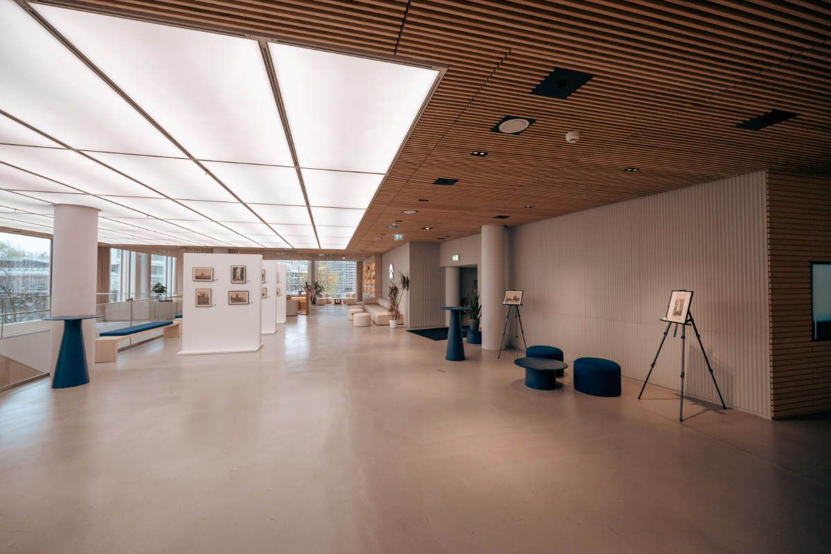 Modern spacious lobby with wood ceiling, blue accent furniture, and art displays in a contemporary building.