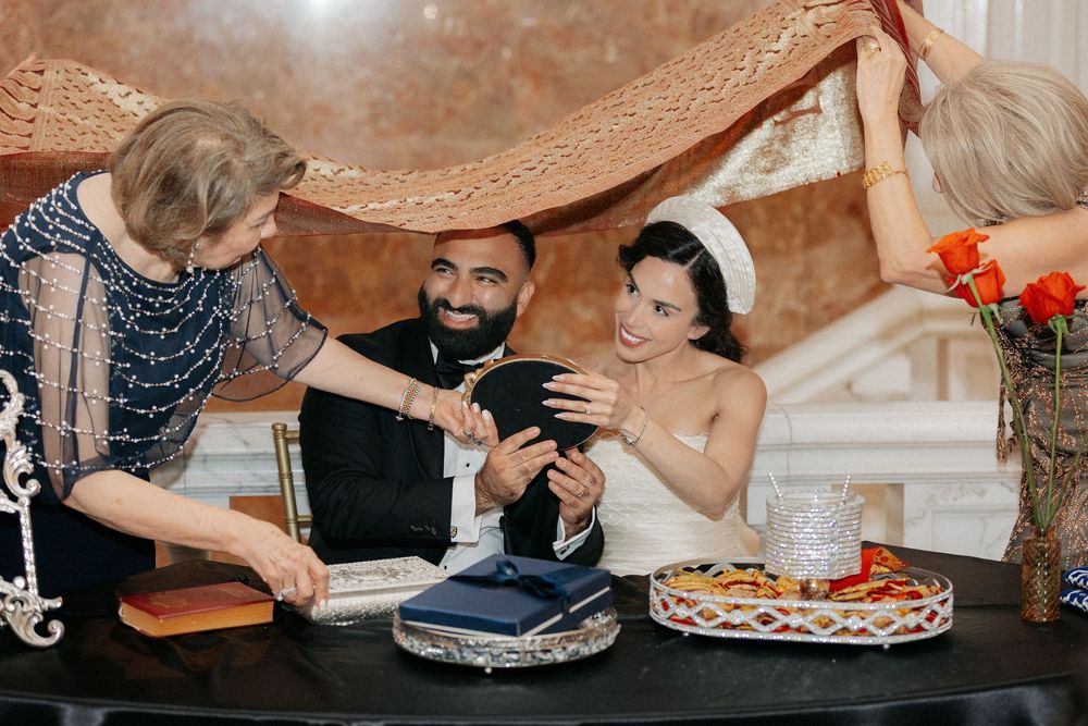 Bride and groom share a joyful moment under a traditional chuppah during their Jewish wedding ceremony.