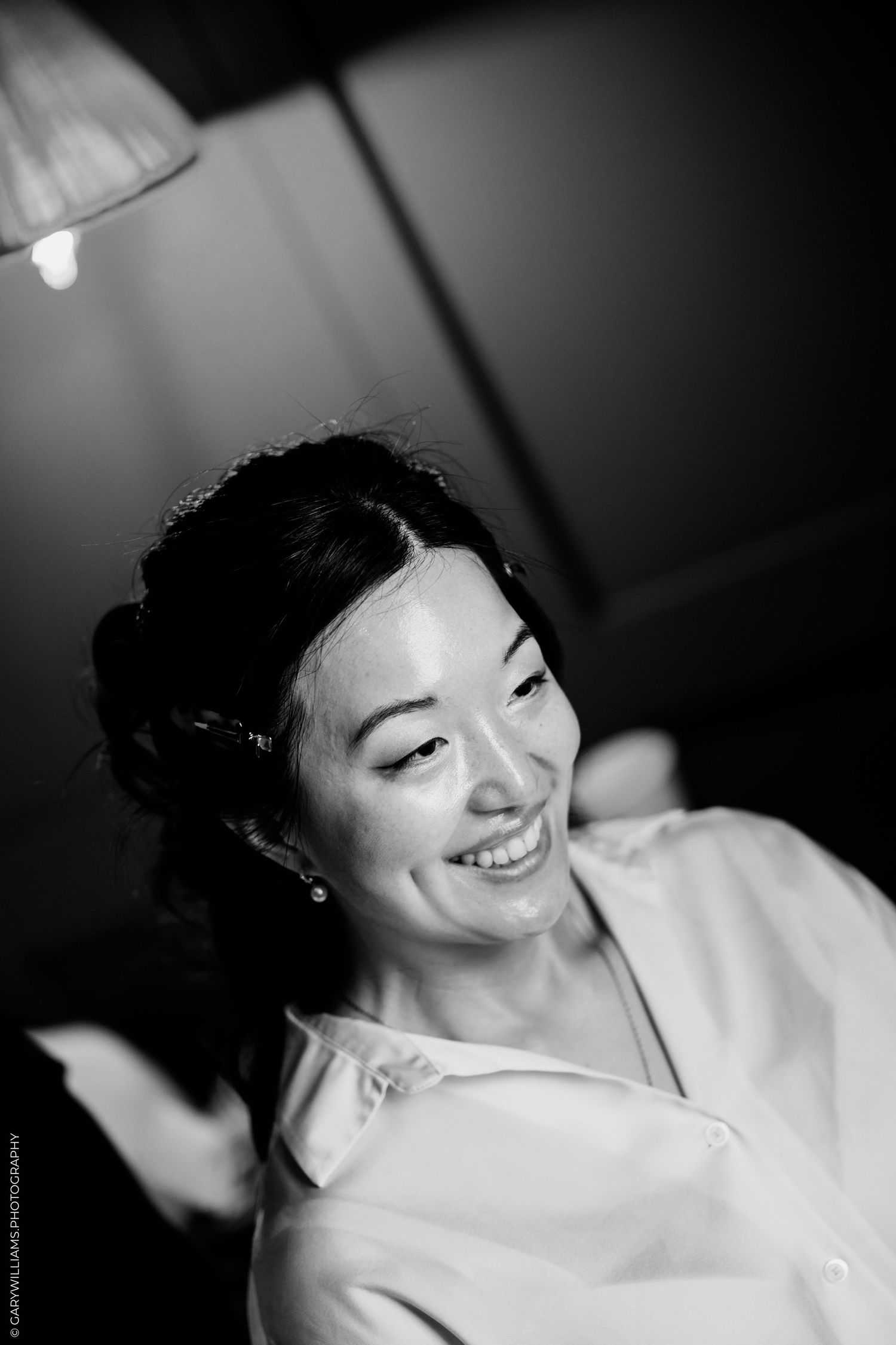 Radiant bride smiles joyfully in black and white portrait during wedding preparations.