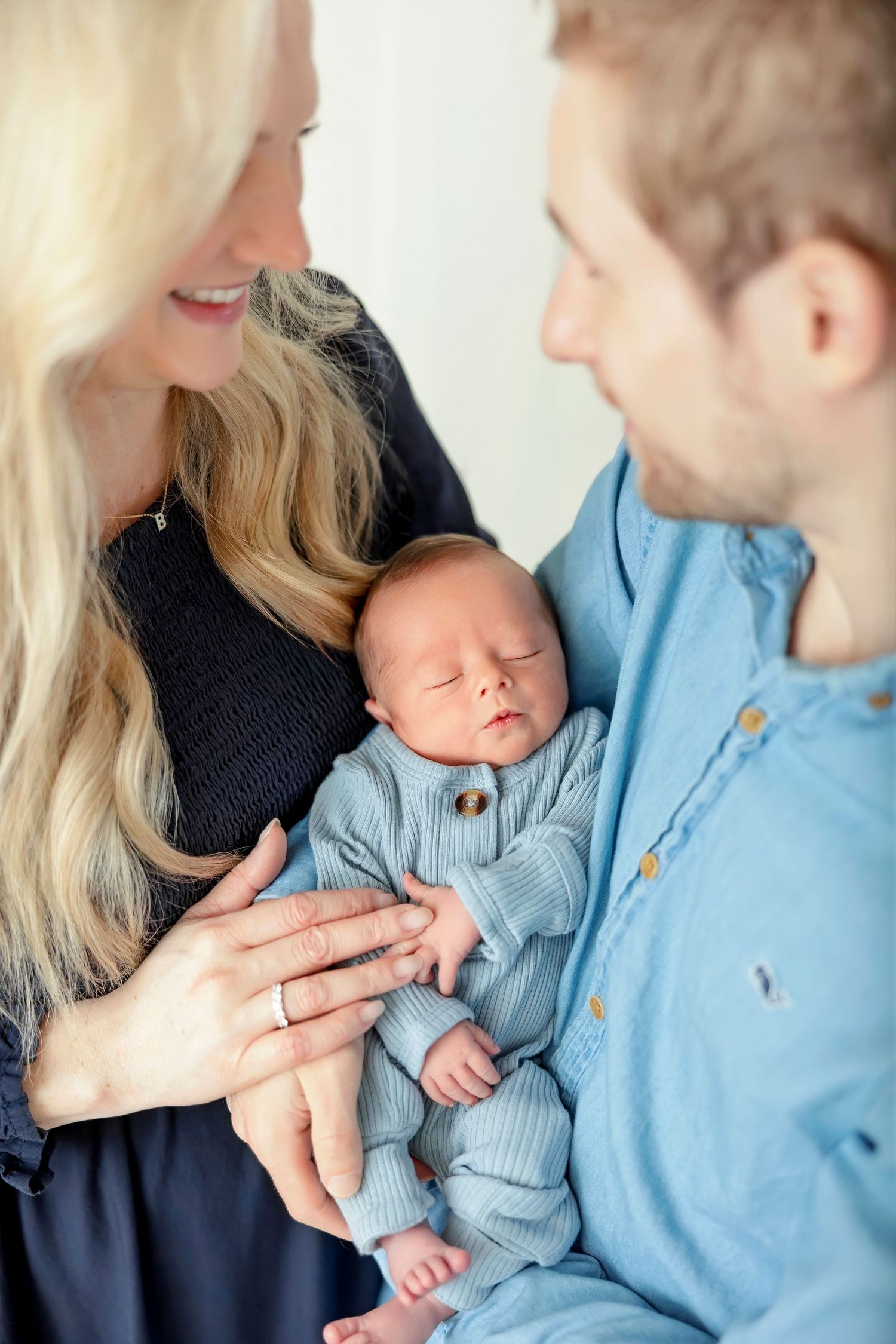 Parents admiring their sleeping newborn son during a studio newborn photography session.