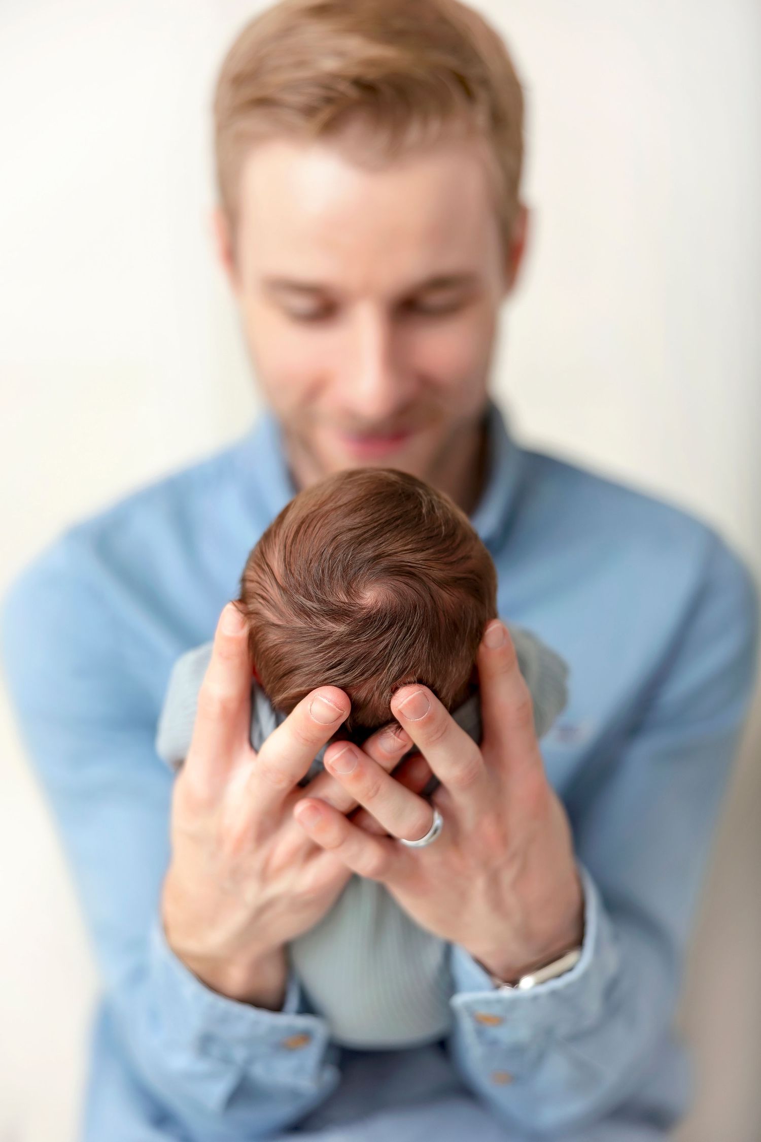 Father holding his sleeping newborn son during a studio newborn photography session in Clear Lake, Iowa.